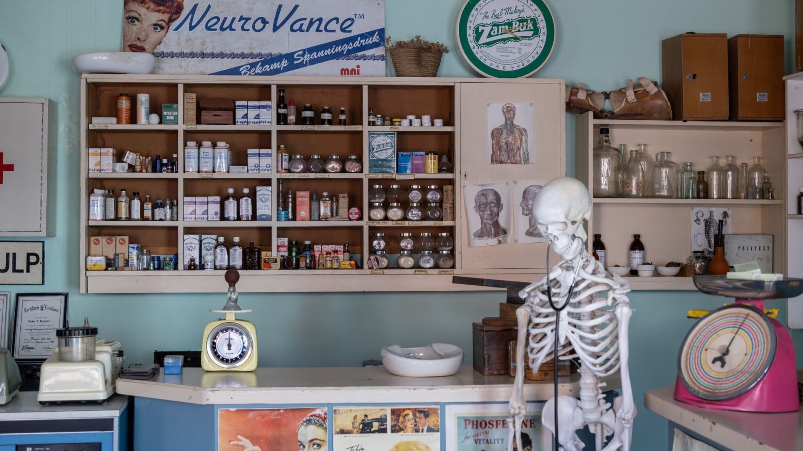A nostalgic view inside an old-timey pharmacy featuring vintage medicine bottles and a medical skeleton on display.