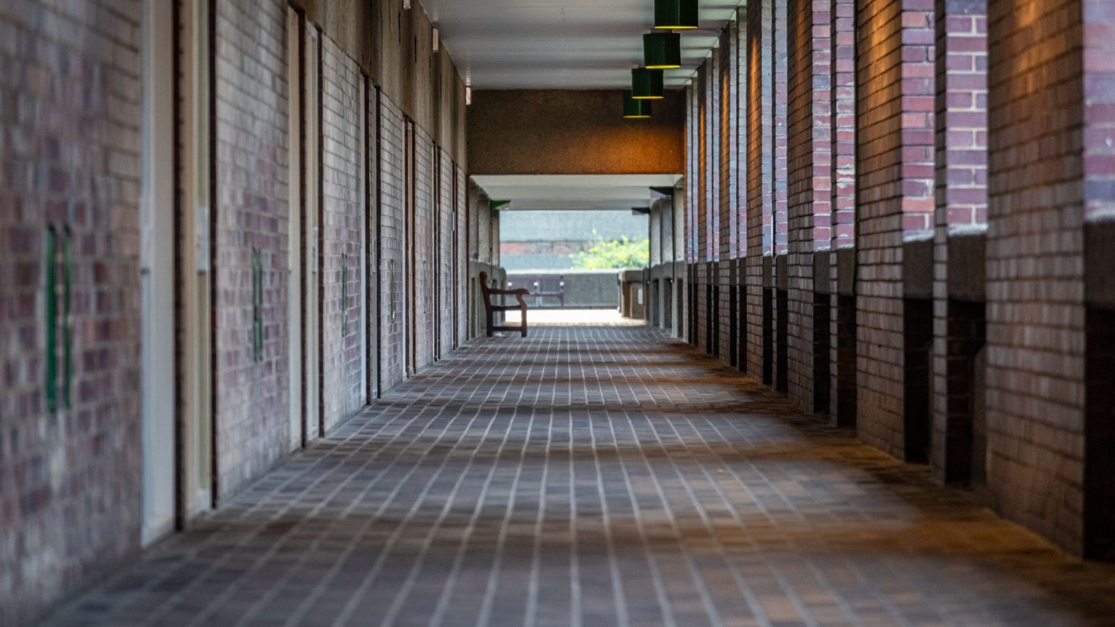 A quiet, empty corridor in Barbican Centre, London with brick walls and ceiling lights.