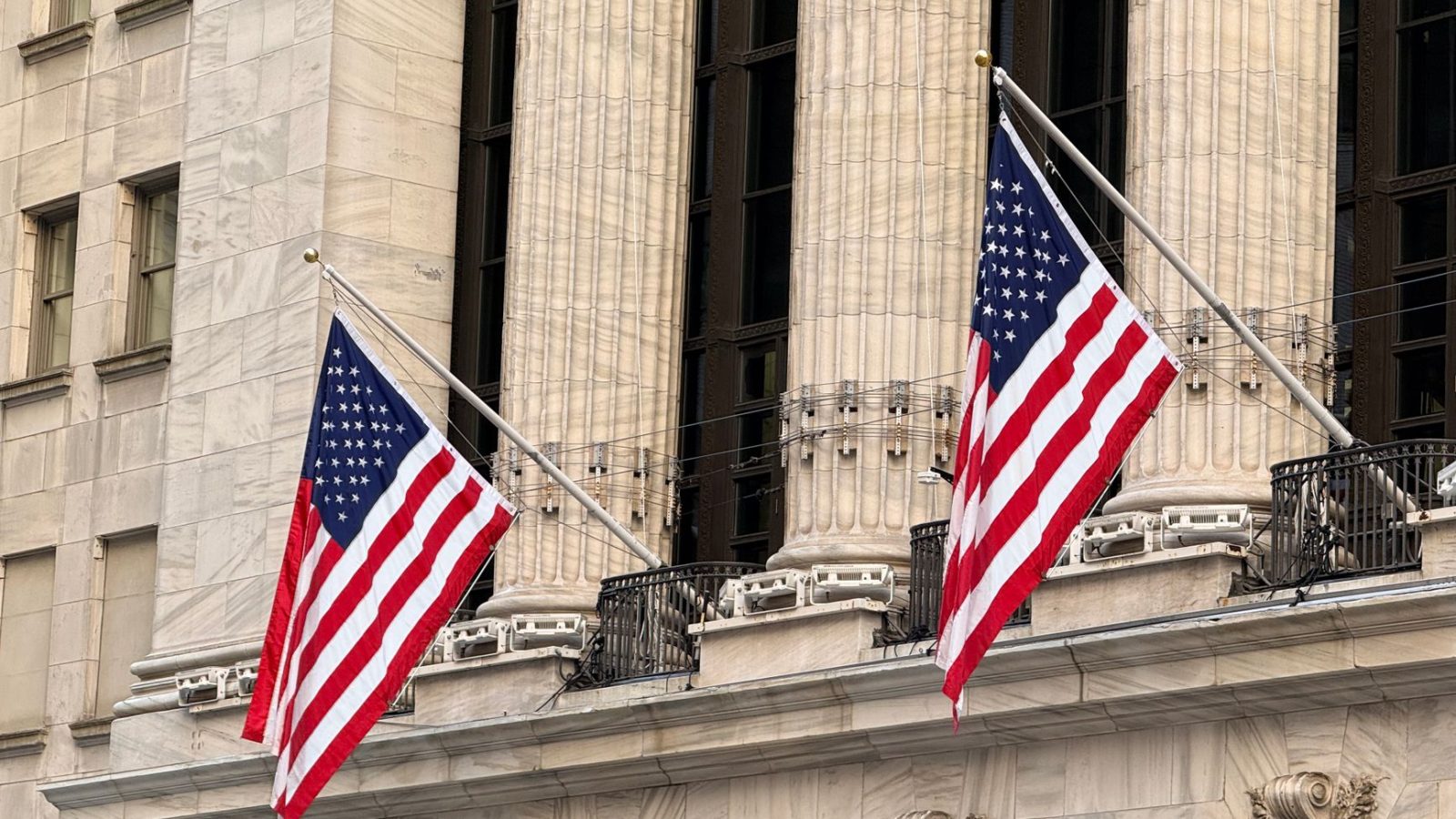 American flags displayed prominently on a historic Wall Street building in New York City.