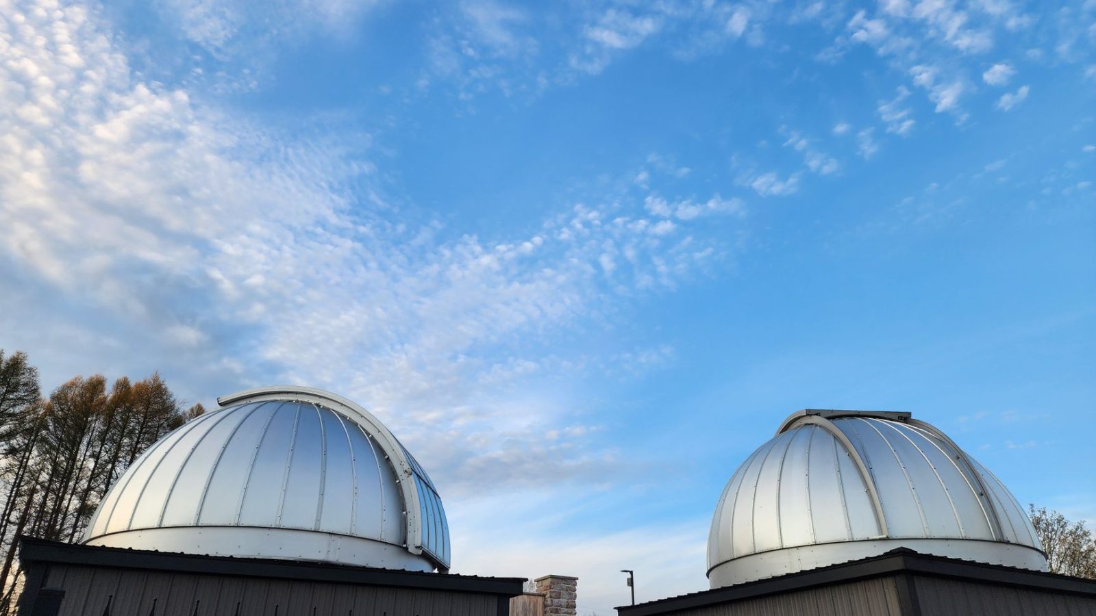 Two modern observatory domes under a blue sky, showcasing scientific exploration.